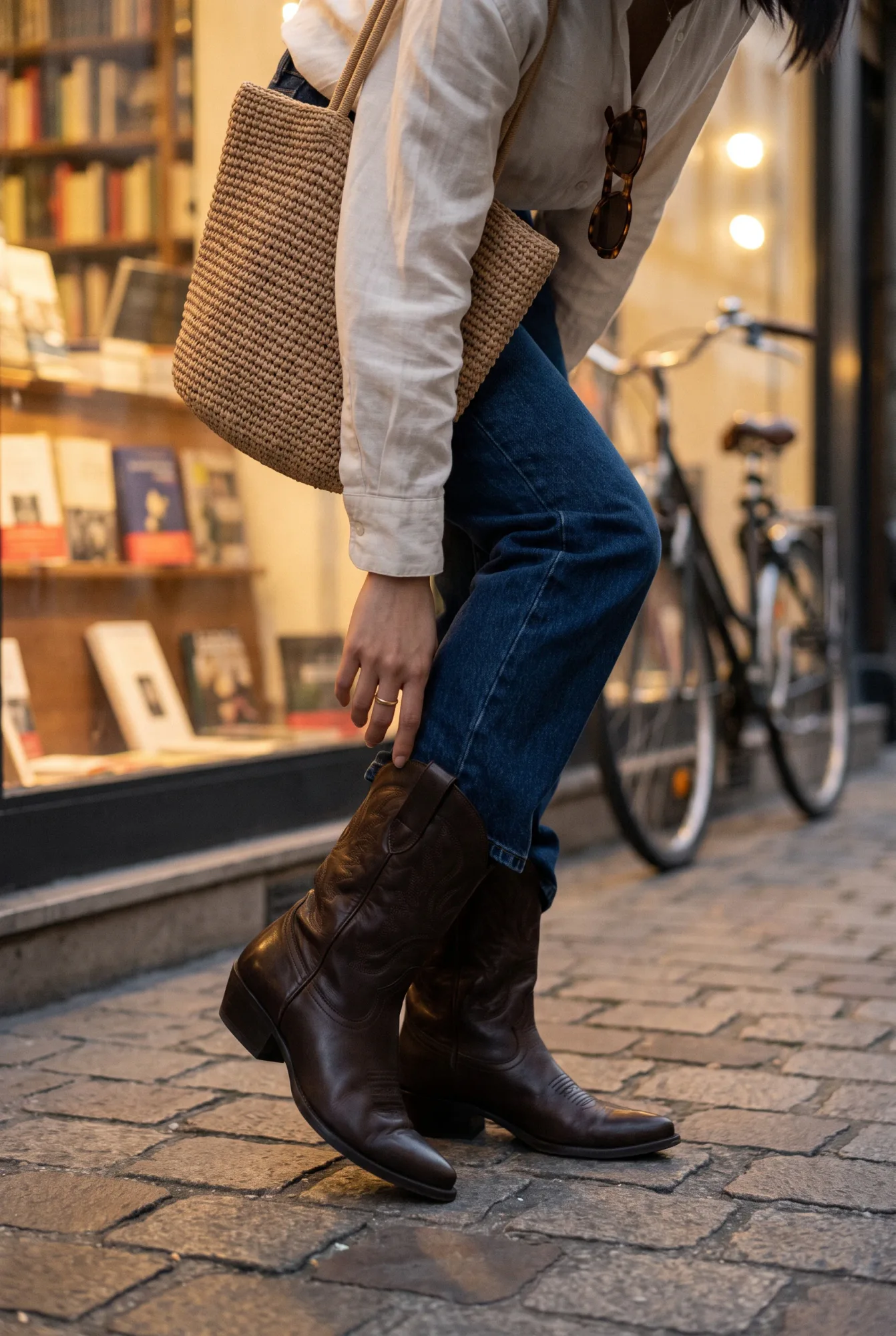Yuna in Amsterdam, a three-quarter frame as she pivots at a bookshop window, wearing dark brown mid-calf Western boots | The Long Way West, Relover