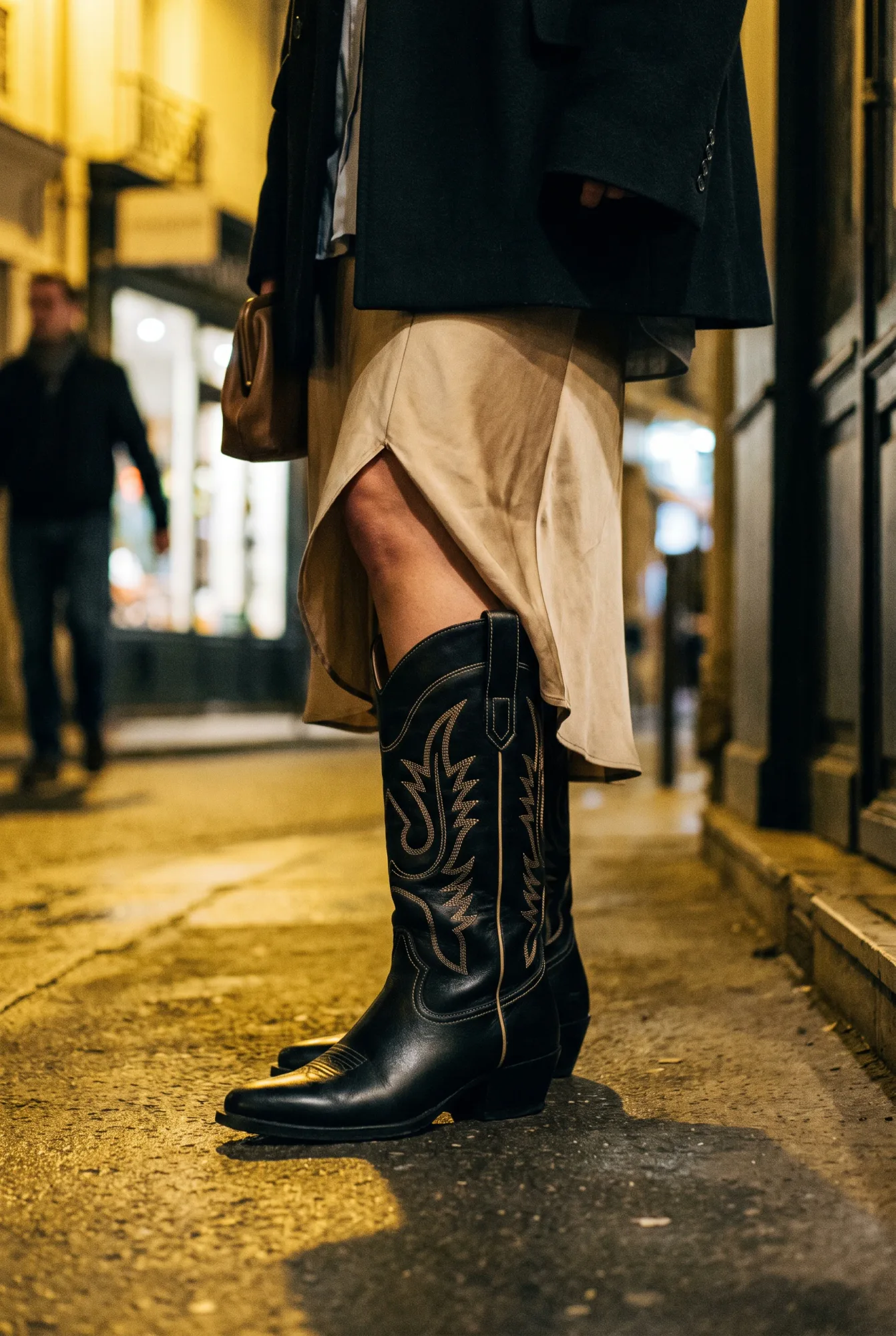 Close crop of a woman's legs wearing a black leather Western boot with pale contrast topstitching | The Long Way West, Relover